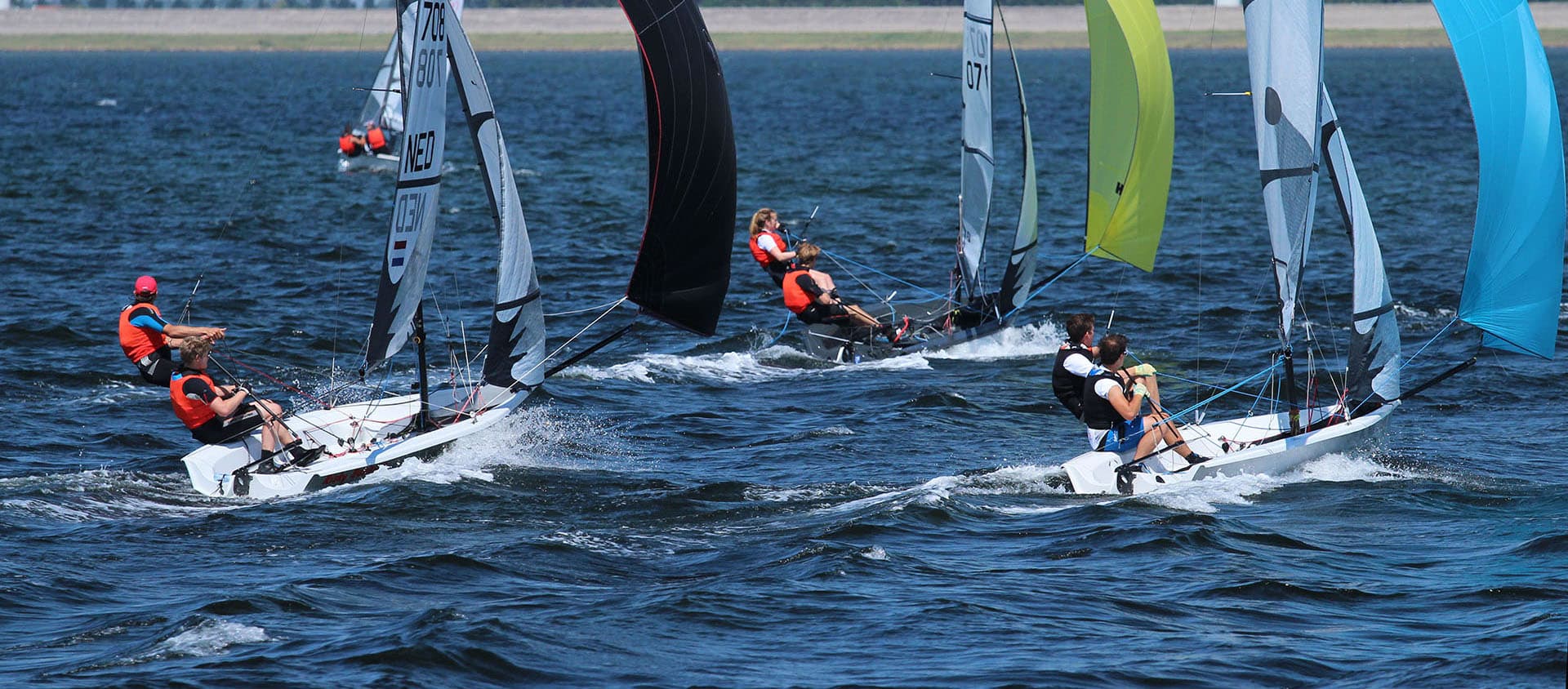 RS500 fleet reaching under coloured spinnakers on open water